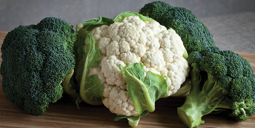 Bunches of broccoli and cauliflower on a wood cutting board