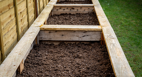 three raised garden beds filled with soil